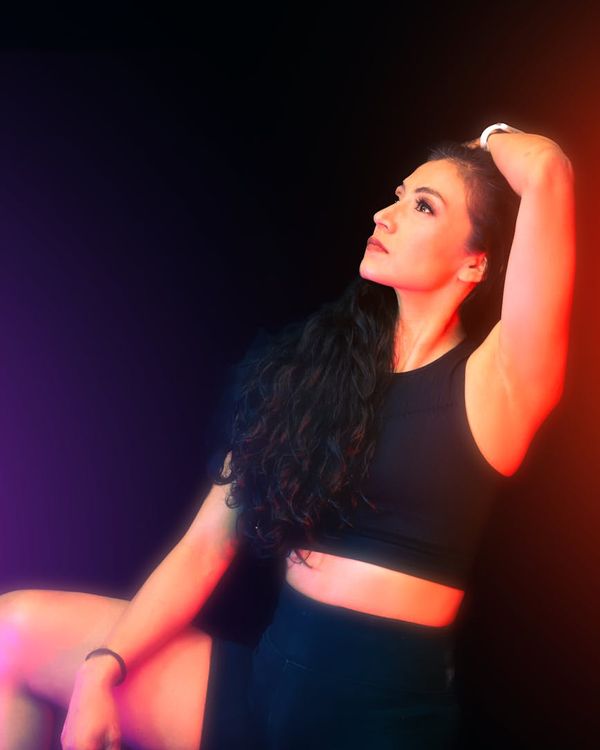 Woman in activewear looking energetic against a dark, atmospheric background.